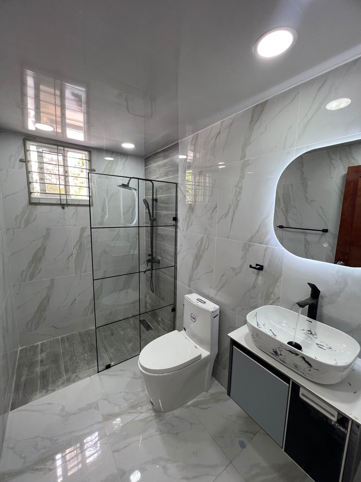 Baño en mármol con mampara de cuadrícula negra