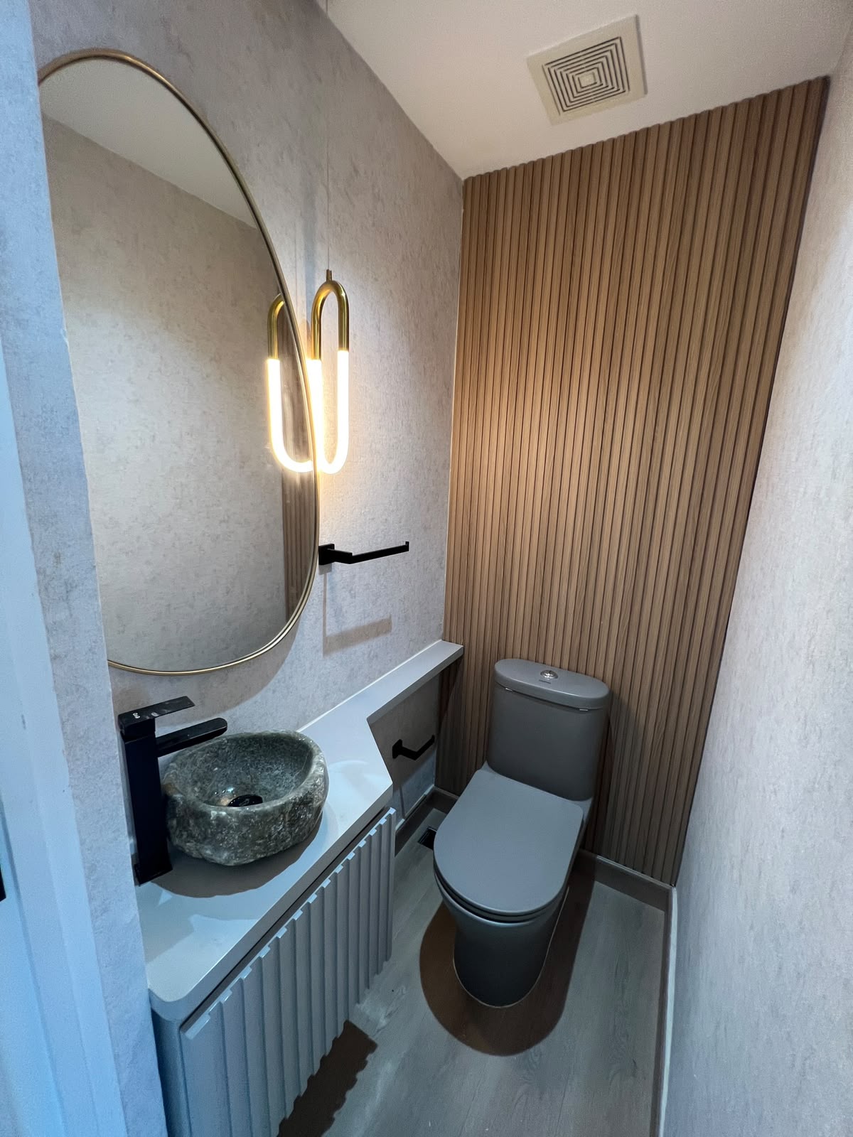Baño de visitas con lavabo de piedra y listones de madera