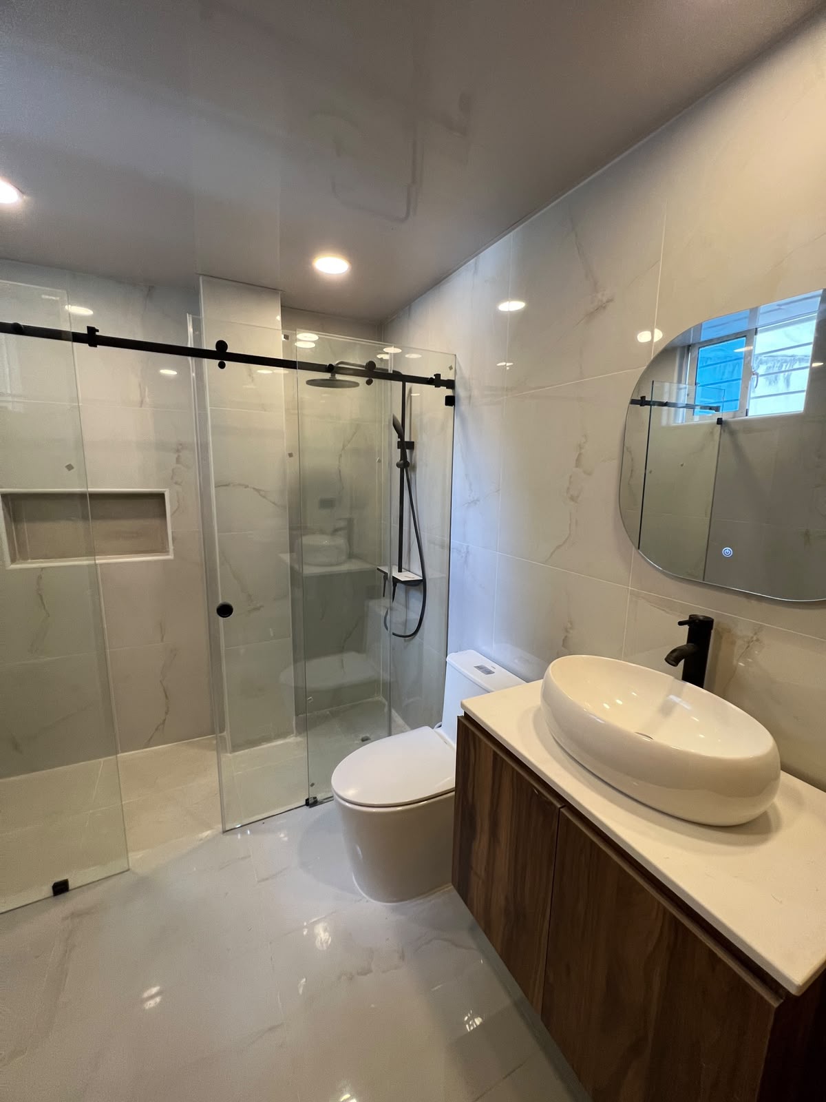 Baño en mármol con vanitorio en nogal